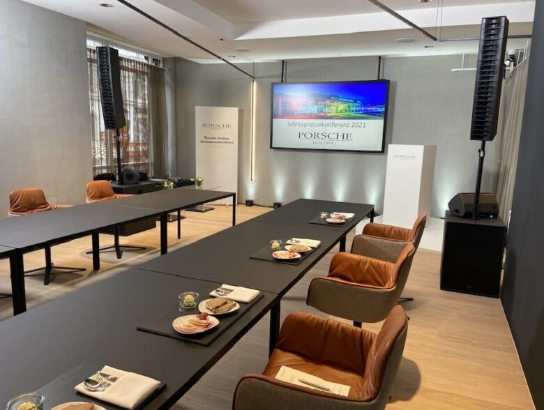 Vorbereiteter Raum für eine Pressekonferenz der Porsche Holding mit Bildschirm und Sitzgruppen