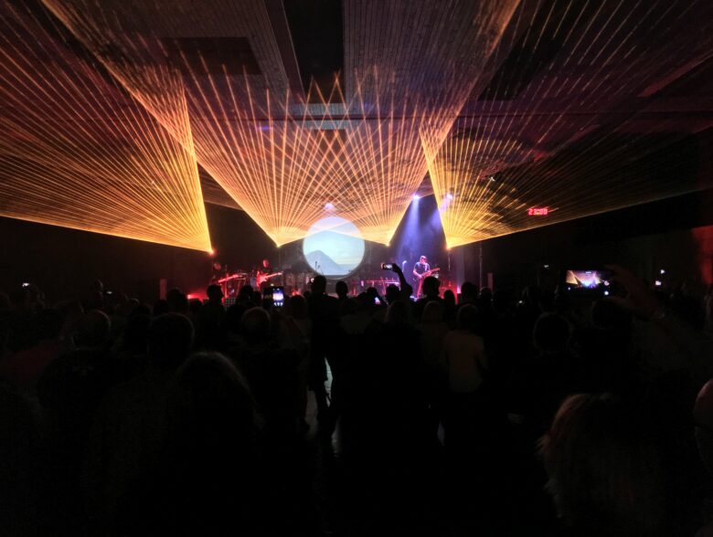 Orange Lichtstrahlen und beleuchtete Kugel über der Bühne bei einem YAF-Konzert in der Schweiz