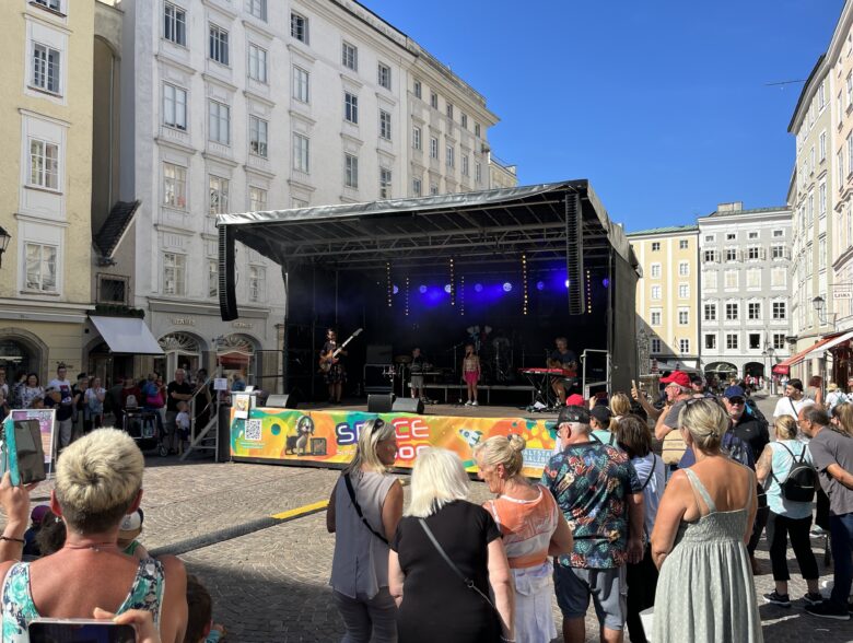 Publikum vor einer mobilen Bühne auf einem Stadtplatz