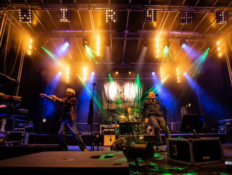 Band auf einer gelb und blau beleuchteten Bühne beim Konzert von Wir 4 in Schärding