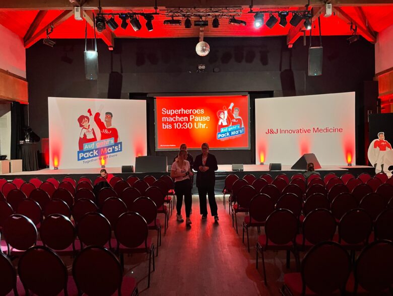 Rot beleuchteter Veranstaltungssaal mit Bühne und Leinwand bei J&J im Aldiana