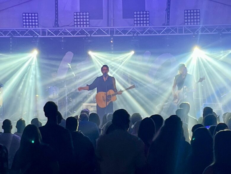 Lemo mit Gitarre unter weißen Lichtstrahlen vor Publikum in Euratsfeld