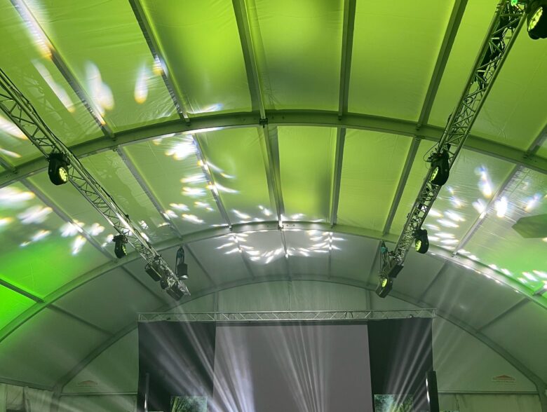 Bühne und weiße Lichtstrahlen im grün beleuchteten Veranstaltungszelt bei Brandmood