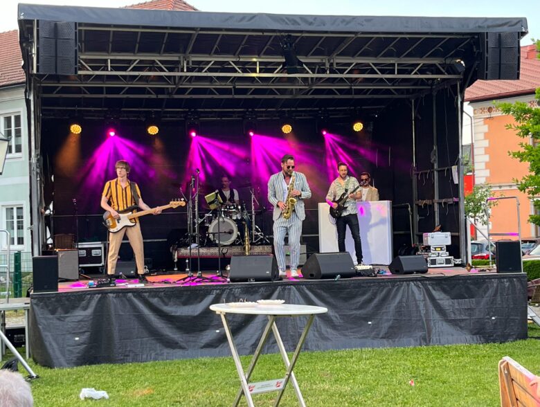 Band auf einer violett beleuchteten mobilen Bühne in Peuerbach